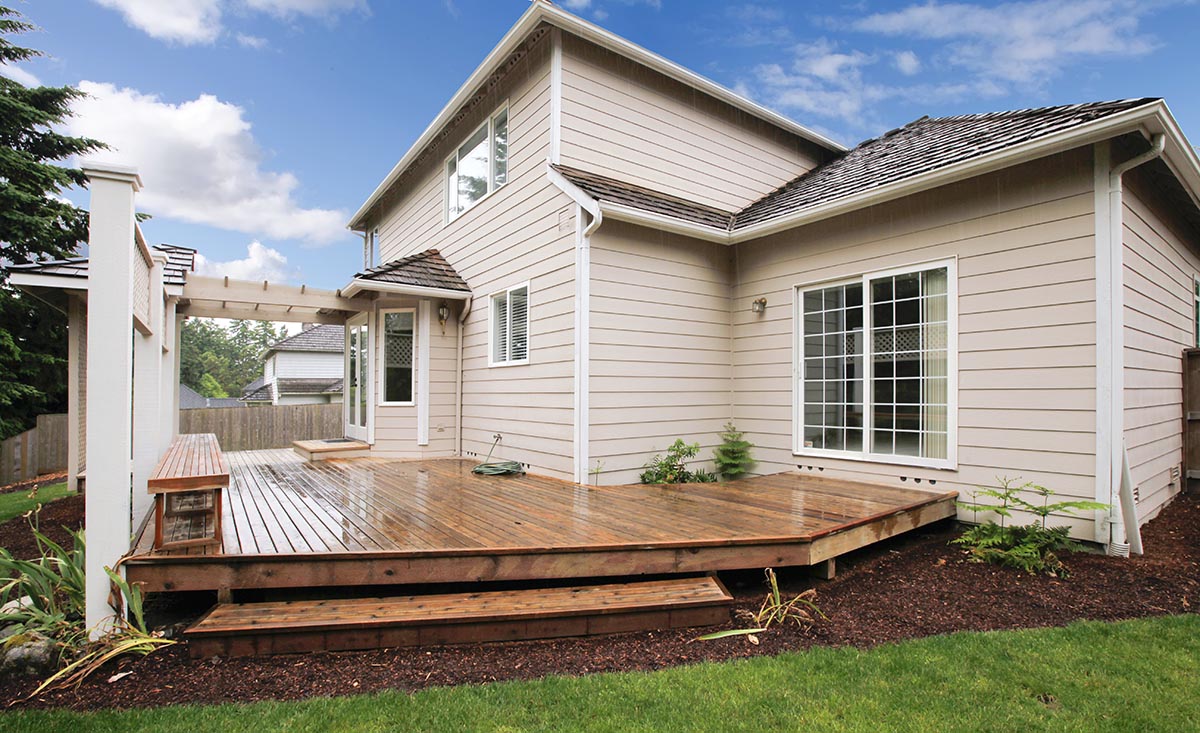 Large beige house with deck seen while preforming home inspection services